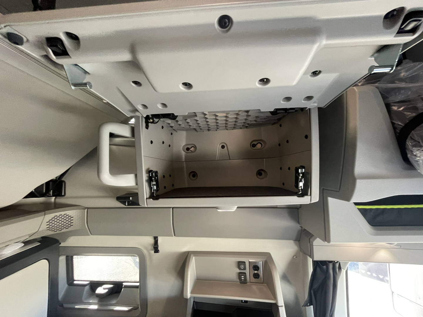 Volvo VNL64T860 cab interior showing overhead storage compartment open with metal latch points and trim panels.