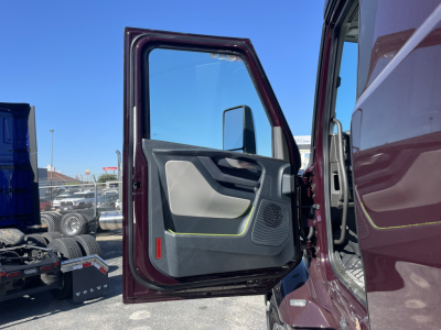 Truck cab door interior and open entry showing Volvo VNL interior panel with grey and black colors, window, and side mirror.