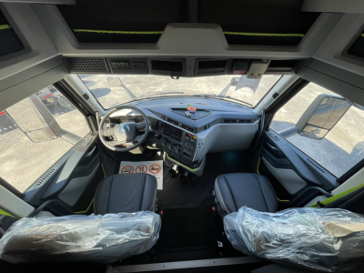 Cab interior of a Volvo VNL64T860 truck showing steering wheel, dashboard, and two front seats wrapped in plastic.