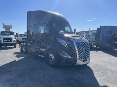 Volvo VNL64T860 truck in dealer lot, front three-quarter view showing aerodynamic cab, chrome grille, and dual rear axles under the trailer.