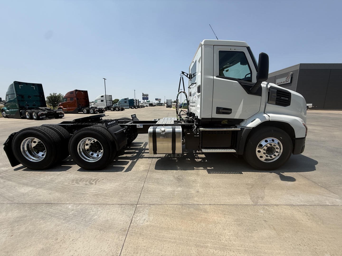 Truck chassis side view showing cab and dual rear axles with fuel tanks and wheels visible.