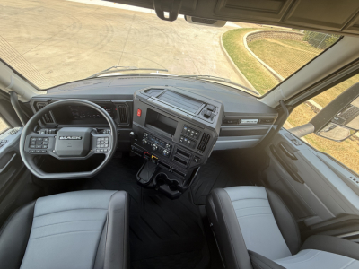 Truck cab interior of a 2027 Mack AN64T showing steering wheel, dashboard, and front seats.