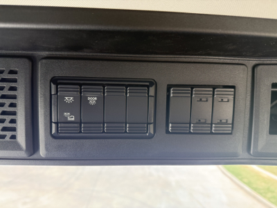 Dashboard switches and panels in a Mack AN64T showing multiple rocker switches; labels include door and light icons.