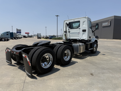 Mack AN64T conventional daycab tractor in pristine condition, three rear axles, white cab, fuel tanks, chassis, and dual rear wheels visible.