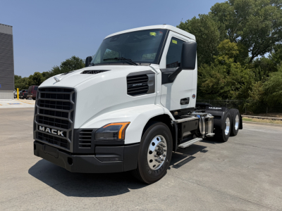 Truck cab front-left view showing Mack grille with MACk branding, large bumper, and side mirrors. Visible text includes MACK on grille and on side of cab.