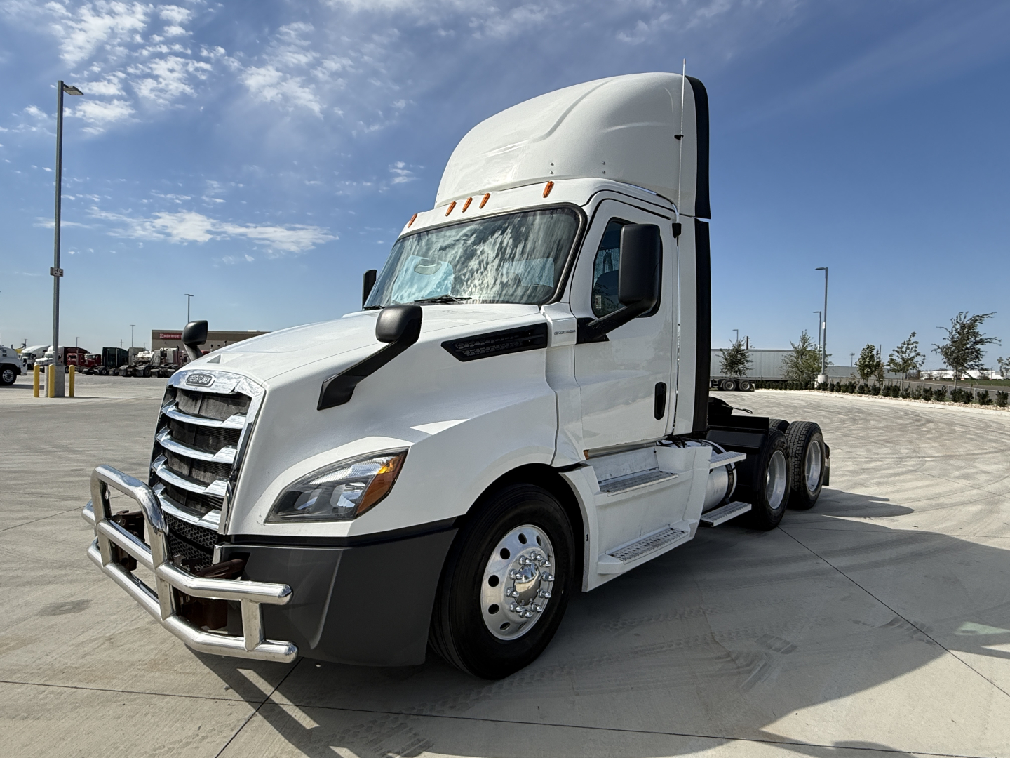 Truck cab and front end of a white Freightliner PT126064S daytime cab showing grille guard and aerodynamic mirrors.