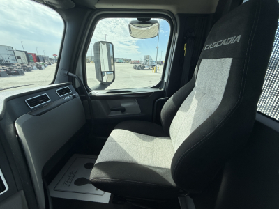 Cab interior of a Freightliner PT126064S Daycab showing driver seat, dash with Casadia label, side window and mirror.