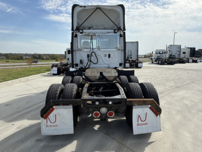 Rear view of a Freightliner semi-truck tractor chassis showing dual rear axles, mudflaps with Brown logo, and rear lighting; white cab, open sleeper area.