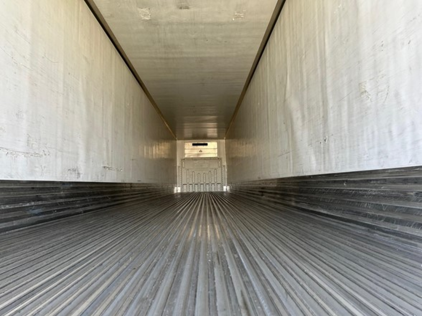 Inside view of a 2018 Utility 3000R W trailer empty cargo area with ribbed floor and white interior walls.