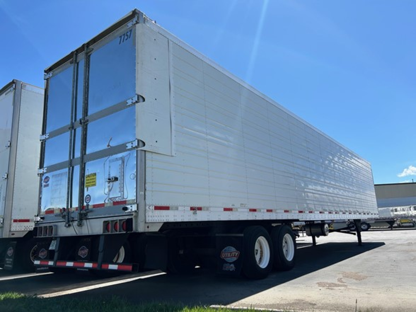 Trailer side and rear view of a white Utility 3000R reefer trailer showing aluminum-sided body, rear doors, and dual rear axles.