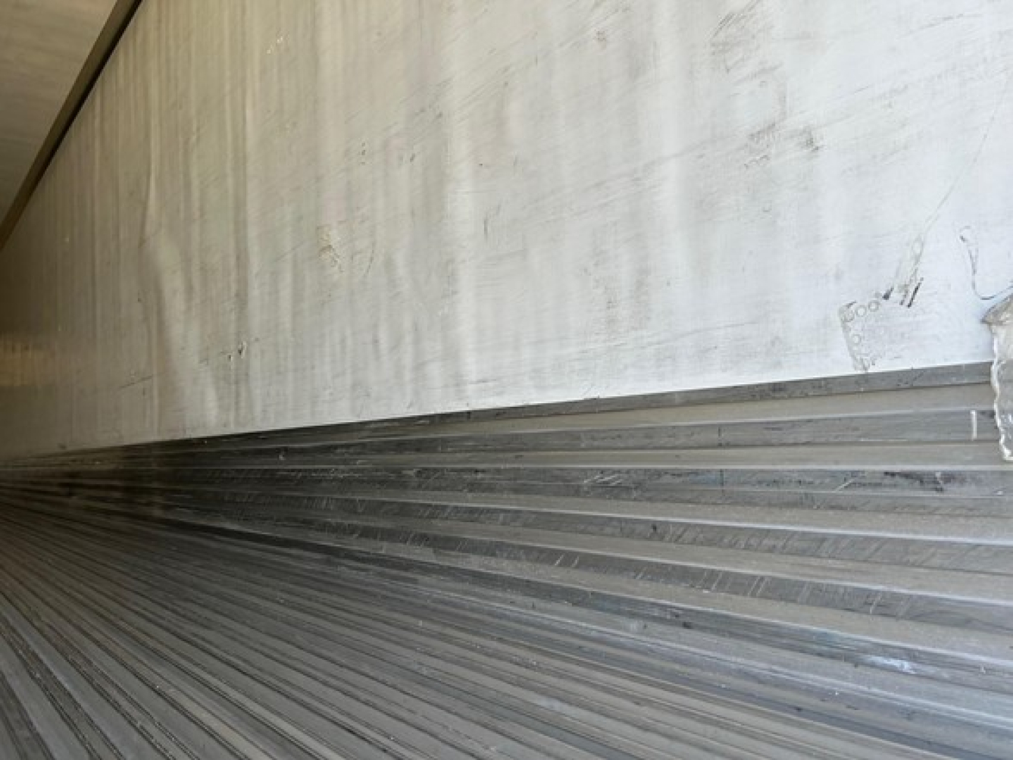Trailer interior edge showing metal ribbed floor with side wall; no additional labels visible.