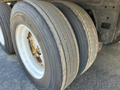 Trailer dual tire axle showing worn tread and steel rim with rust on hub area.