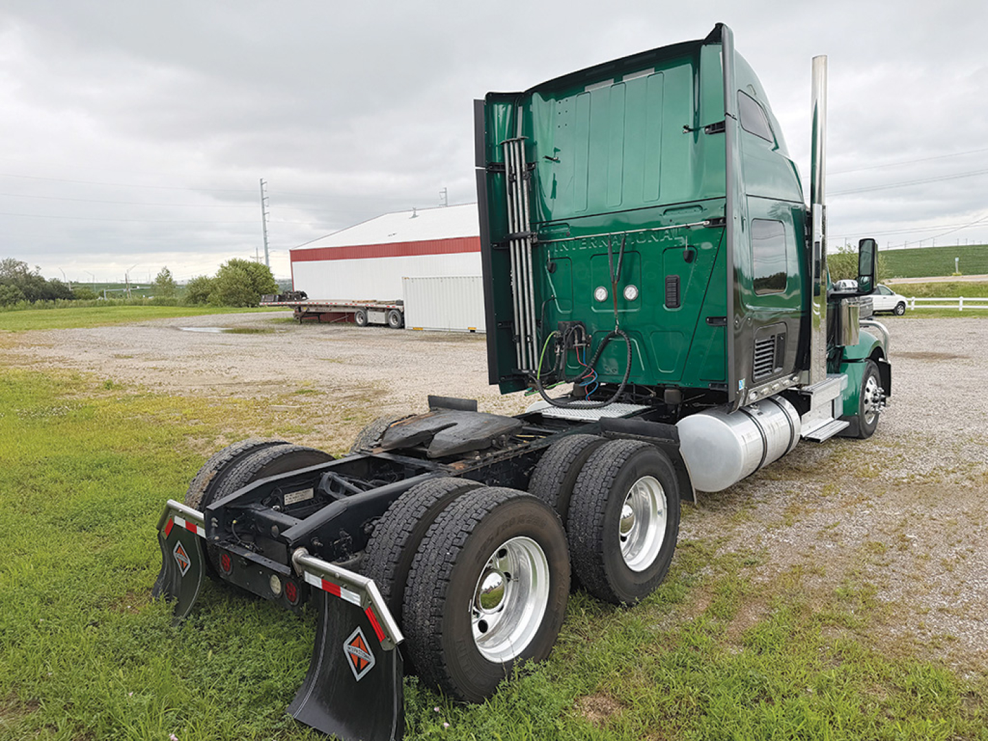 Truck chassis and cab of a green 2022 International LoneStar conventional sleeper, rear view showing dual rear axles, fifth wheel area, and fuel tanks.