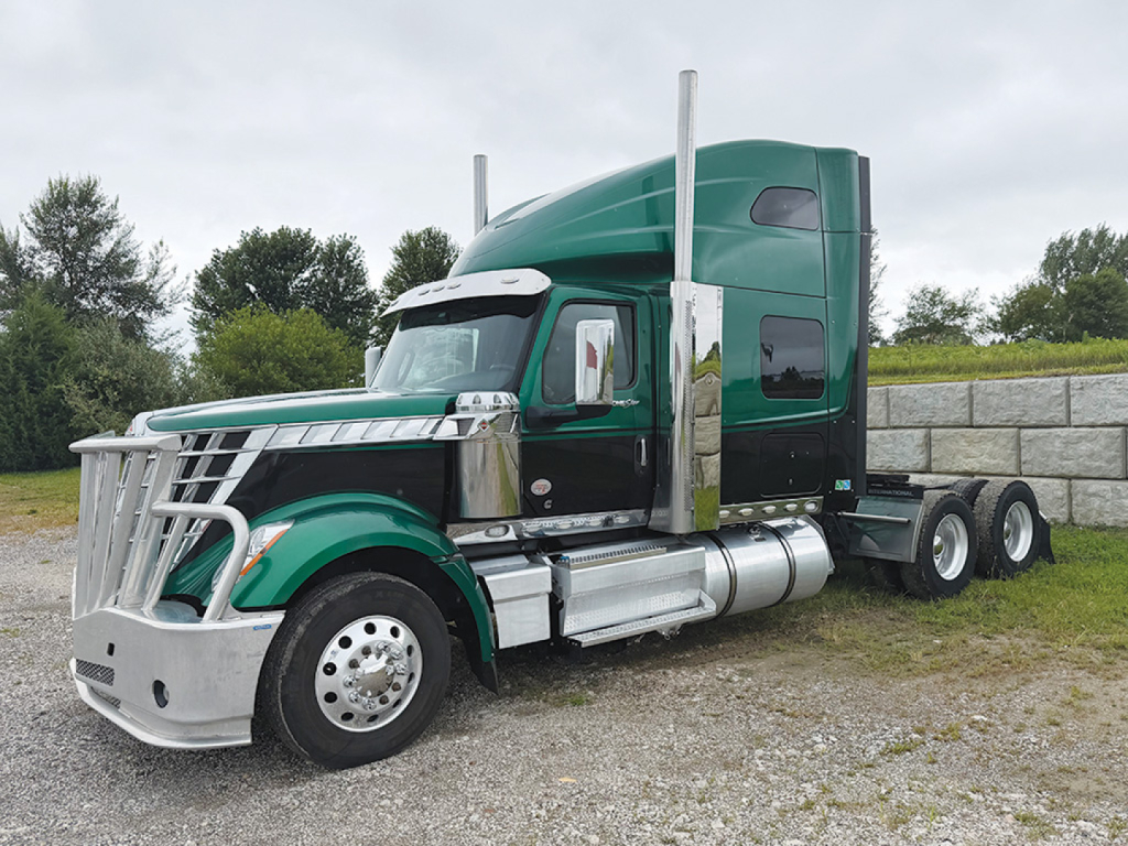 Truck: green 2022 International LoneStar sleeper tractor, side view showing chrome bumper, dual fuel tanks, exhaust stacks, and extended cab with high roof; stock number 555649.