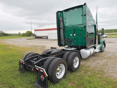 Truck chassis and cab of a green 2022 International LoneStar conventional sleeper, rear view showing dual rear axles, fifth wheel area, and fuel tanks.