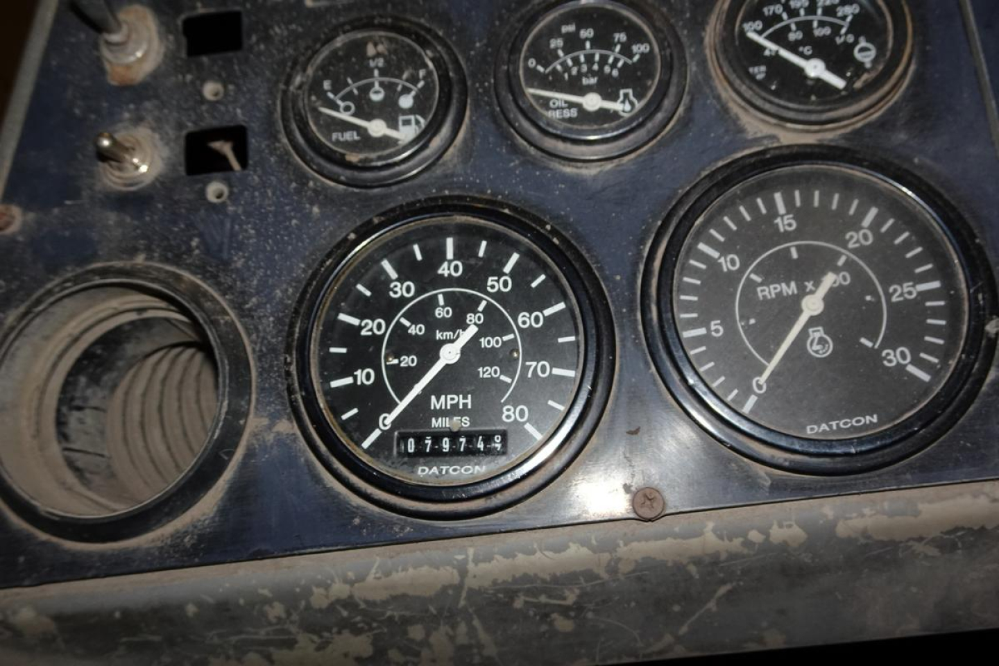 Dashboard panel with multiple gauges including speedometer showing MPH, odometer reading 019,? miles, RPM gauge, fuel, air pressure gauges; Datcon labeling visible.