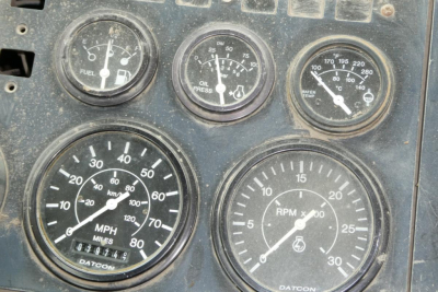 Dashboard gauges showing fuel, oil pressure, water temp, mph odometer, and rpm gauges on a weathered truck panel.