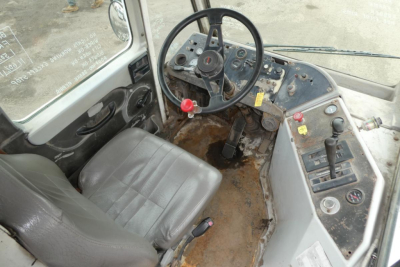 Interior of a 2006 Ottawa 30 yard truck cab showing steering wheel dashboard and worn floor with dirt and controls.