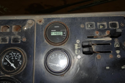 Dashboard panel of a used truck showing an hour meter reading 84560.1 hours, a voltmeter, and various switches in a dusty, worn control cluster.