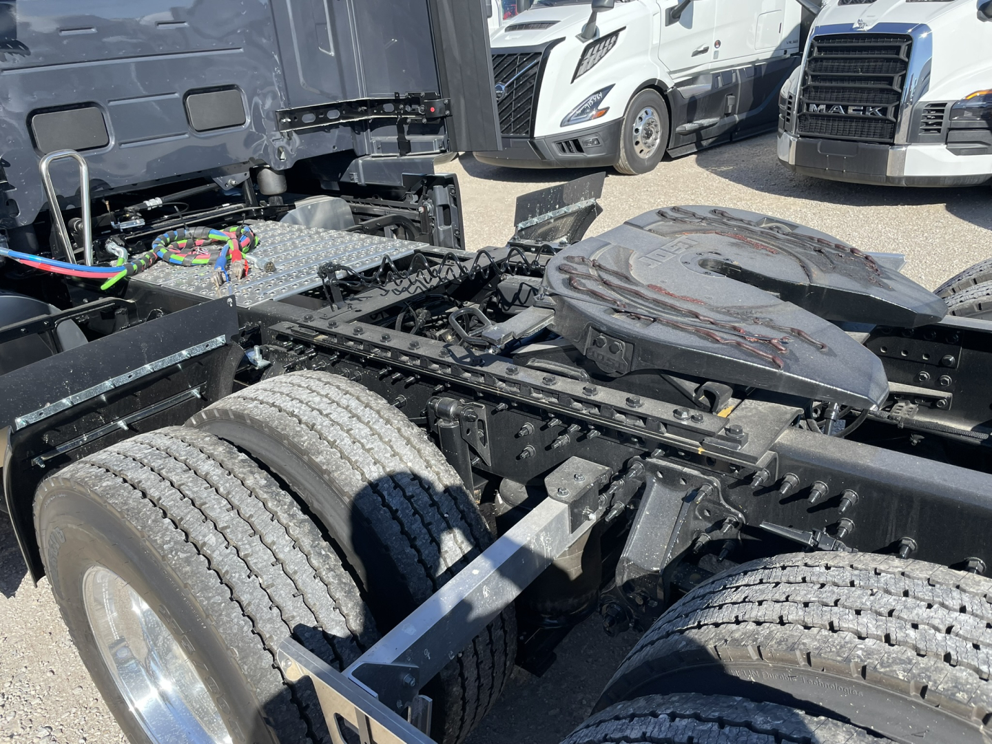 Volvo VNL truck chassis showing rear dual-tire arrangement and exposed battery/air line harnesses with fender and spare tire on the fifth wheel area.