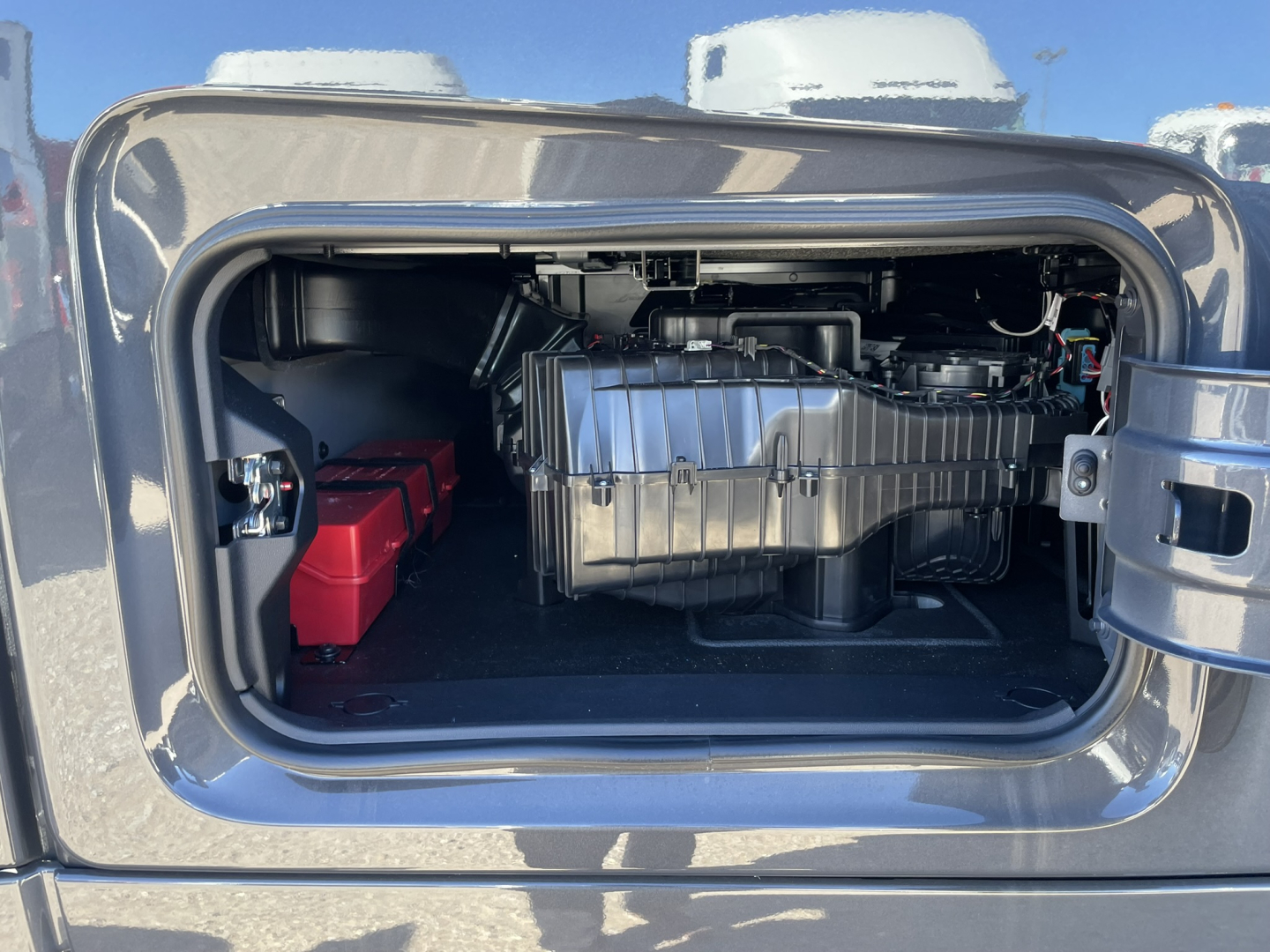Volvo VNL64T860 engine bay access showing large metallic battery box and auxiliary components in front storage compartment.