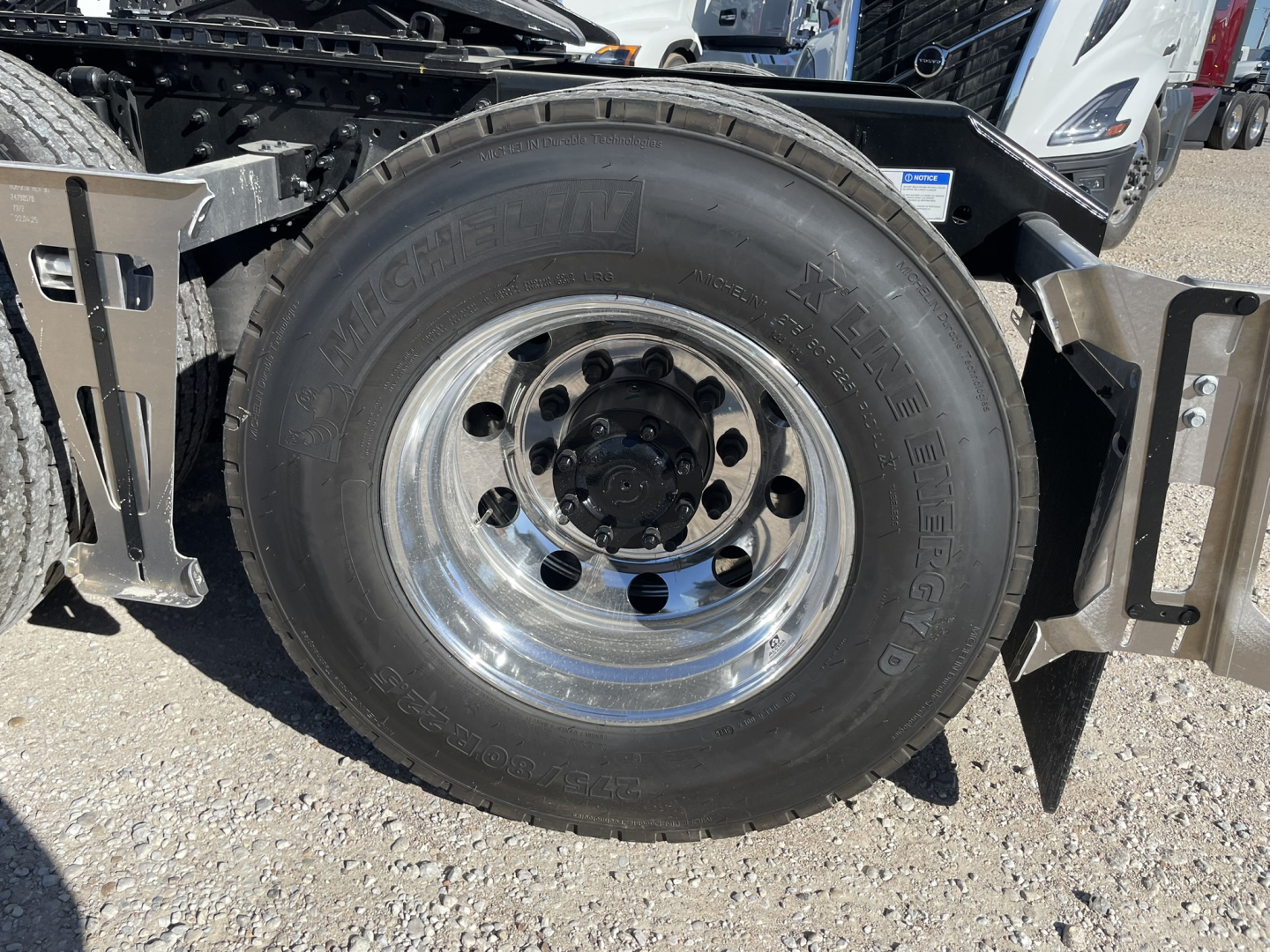 Volvo VNL64T860 front wheel assembly showing Michelin XDN2 endurance tire and polished steel rim with hub and surrounding chassis components.