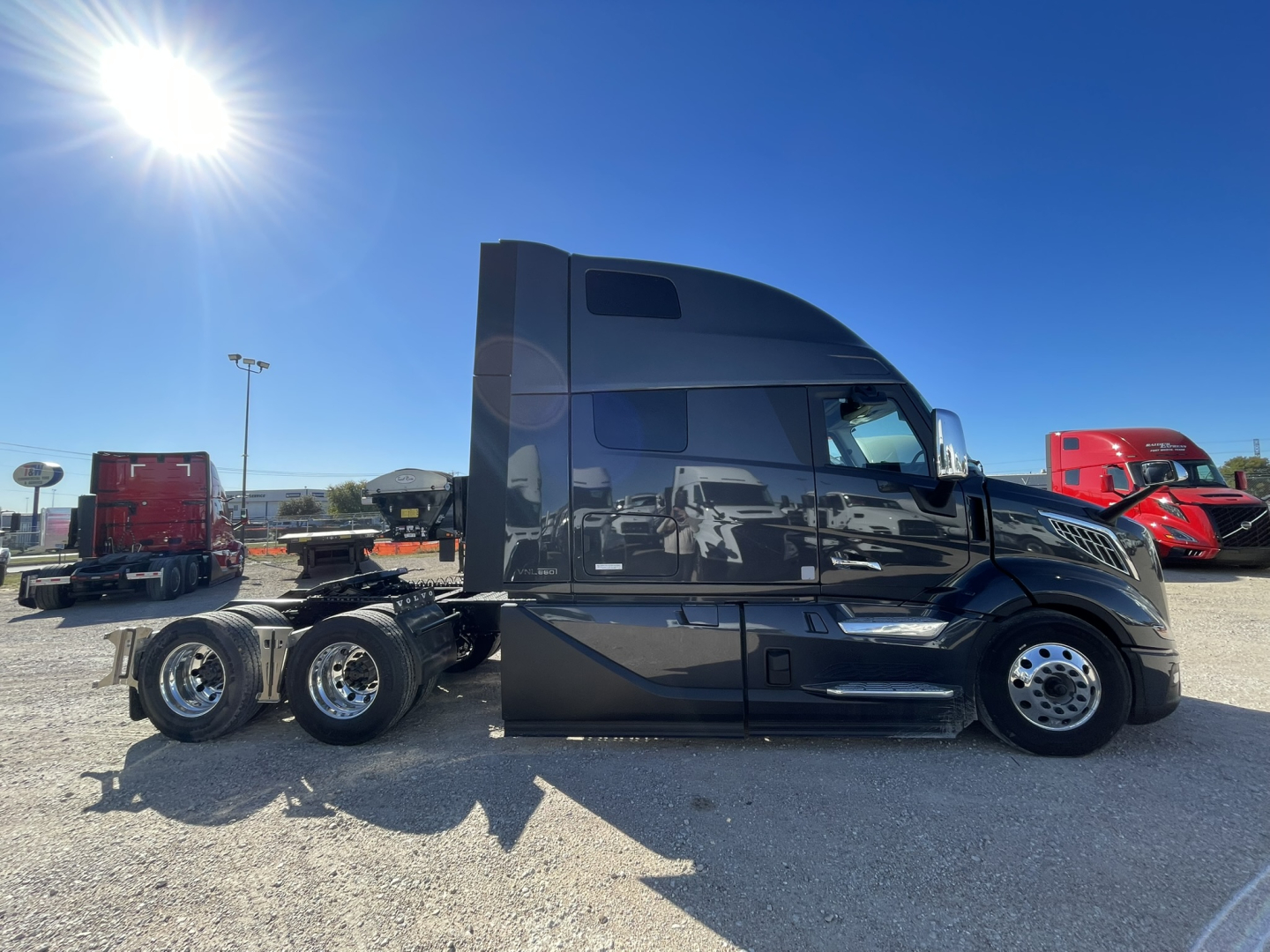 Volvo VNL64T860 truck side view showing sleeper cab and triple-axle rear, black exterior.