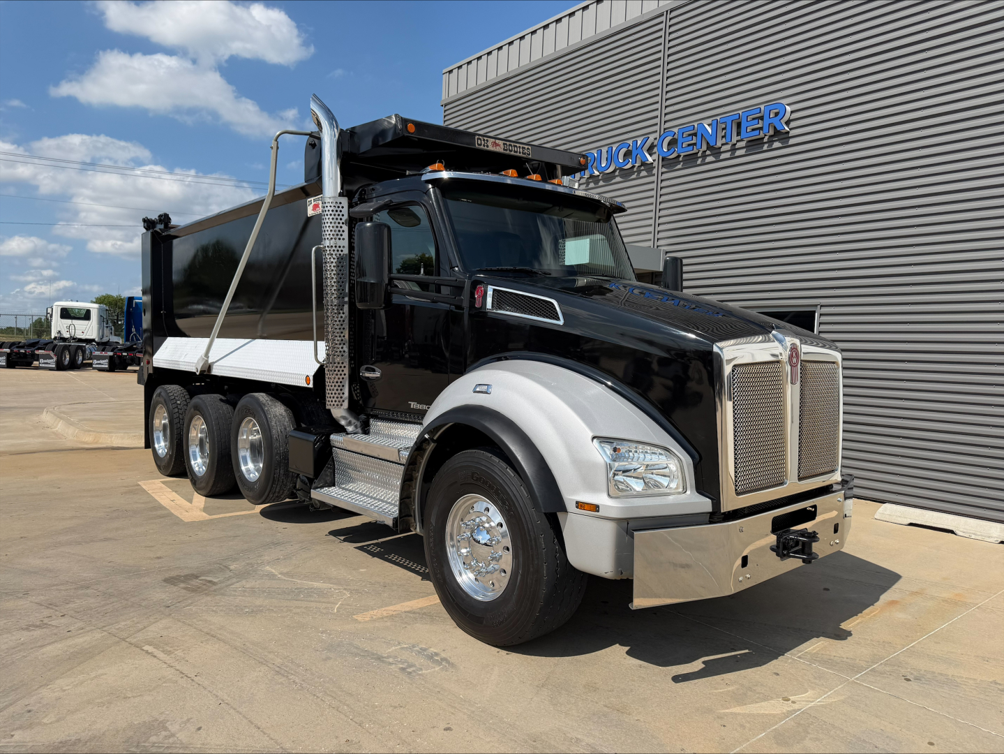 Kenworth T880 dump truck in black and white with chrome front, three-axle configuration, logo grille, and side mirrors.