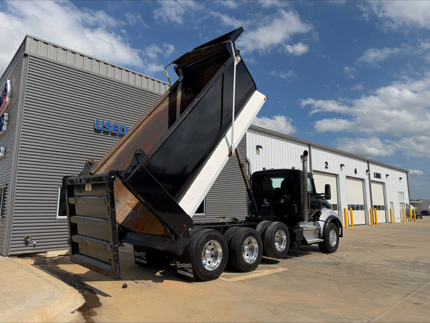 Kenworth T880 dump truck in service with raised bed showing rear and side view with multiple axles.