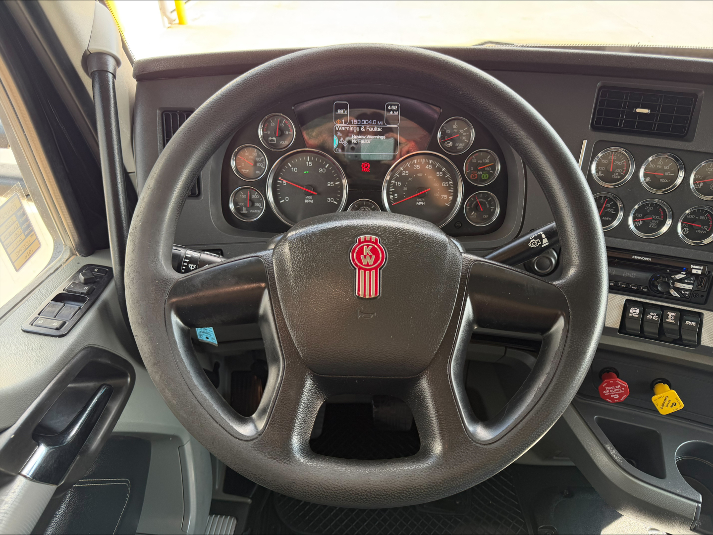 Kenworth T880 steering wheel and dashboard showing gauges, switches, and gear indicators in cab interior.