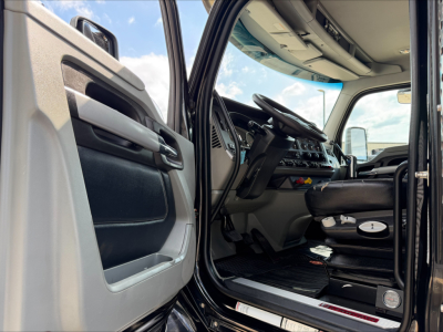 Kenworth T880 cab interior view from open driver door showing steering wheel dashboard and driver's seat.