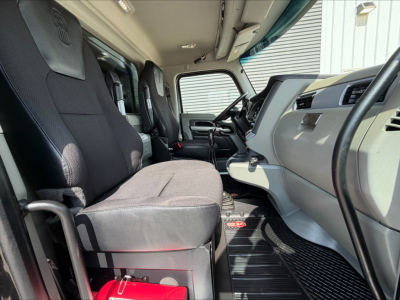 Kenworth T880 cab interior showing driver and passenger seats, dashboard, steering wheel, and center console in a used dump truck.