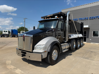 Kenworth T880 dump truck in serviceable condition, black cab with chrome grille, large chrome bumper, dual rear axles under yellow dump bed, clear weather.