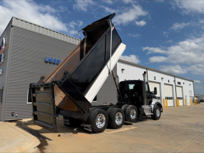Kenworth T880 dump truck in service with raised bed showing rear and side view with multiple axles.