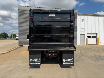 Kenworth T880 dump truck rear view showing dump bed tailgate, mud flaps with Bruckner’s Oklahoma City logo, and chassis under the bed.