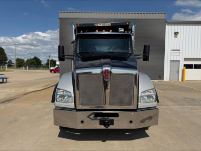 Kenworth T880 dump truck front view showing bold chrome grille, large bumper, dual mirrors, and roof-mounted clearance lights.