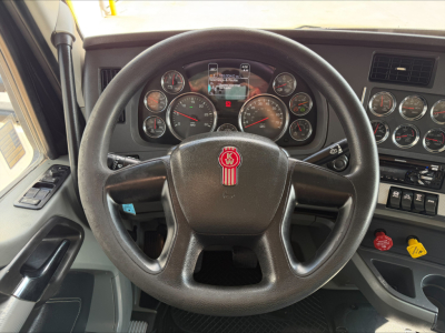 Kenworth T880 steering wheel and dashboard showing gauges, switches, and gear indicators in cab interior.