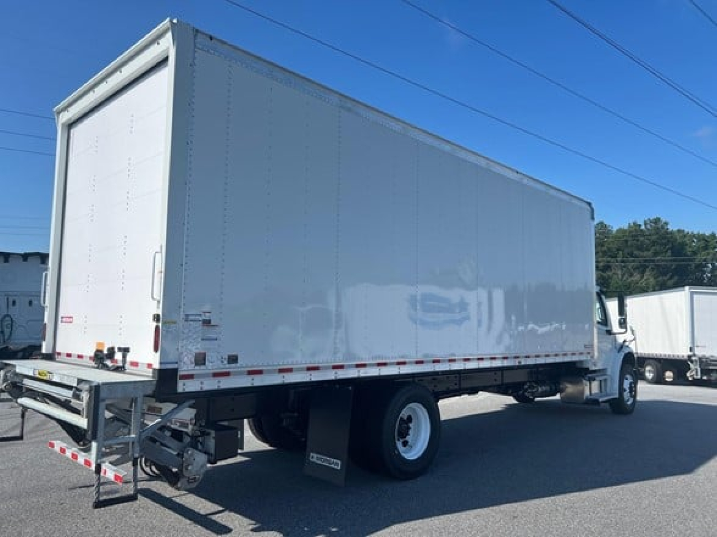 Box truck on a lot showing Freightliner M2 106 Plus with white cargo box and cab, side view, undercarriage, wheels, and stock number 343686.