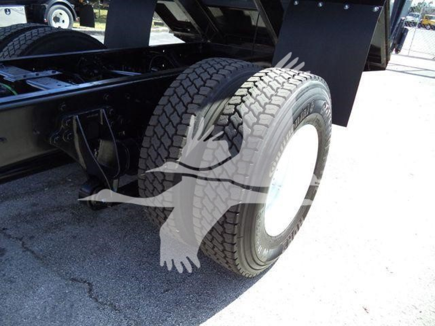 Truck rear view showing dual rear axle and tire on International 4300 dump truck with suspension and chassis components visible.