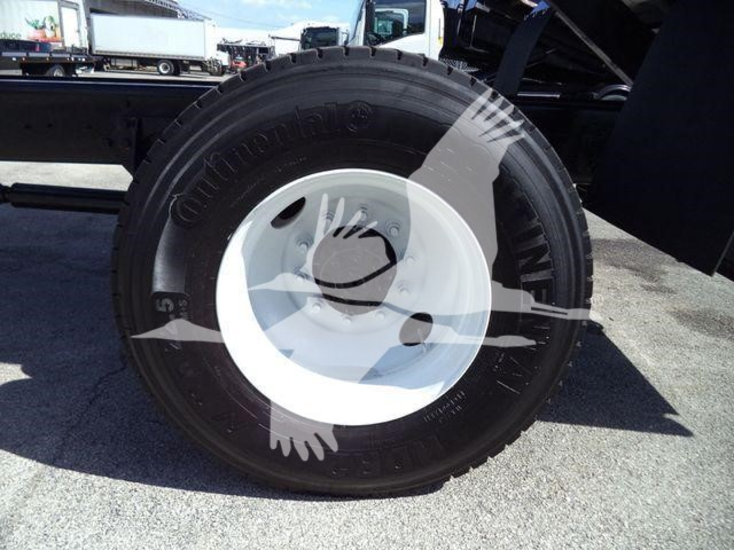 Wheel assembly showing Continental tire mounted on white steel rim attached to a dump truck chassis.