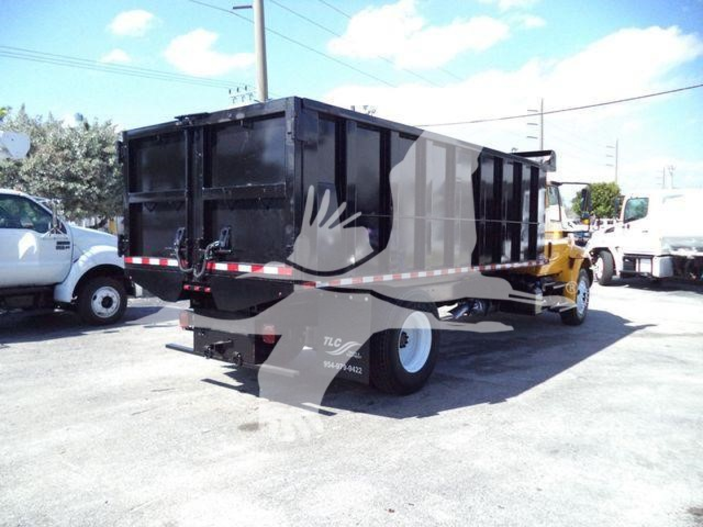 Dump truck bed on a 2019 International 4300 with black container, rear view showing taillights and bumper, in-service conditions