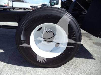 Wheel assembly showing Continental tire mounted on white steel rim attached to a dump truck chassis.