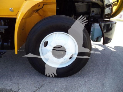 Truck wheel and front fender of a 2019 International 4300 dump truck showing front wheel and bumper area.