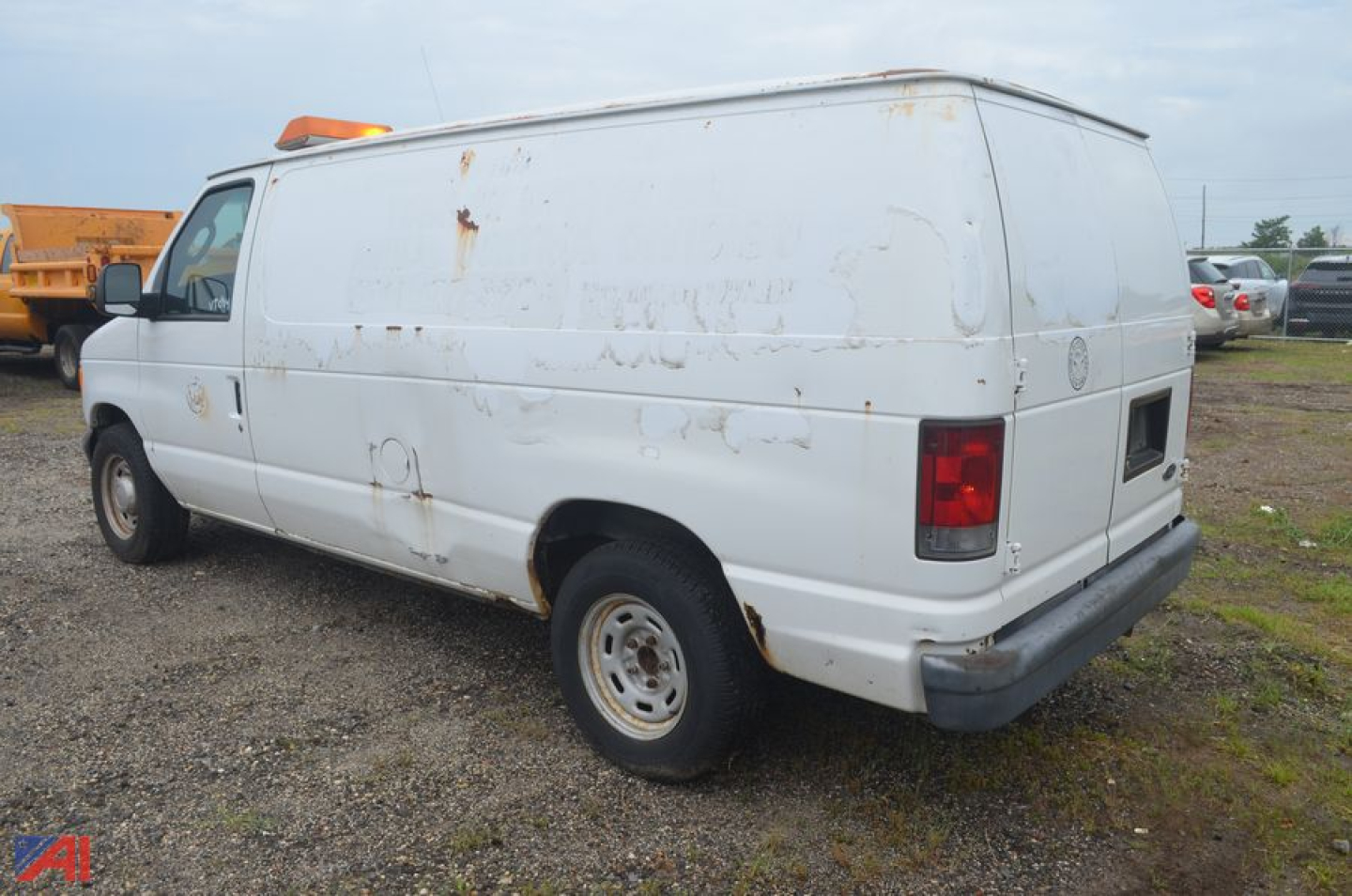 Ford Econoline full-size cargo van, rear/side view, white, with rust patches and utility markings.