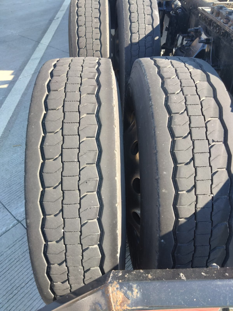 Trailer axles with twin tires showing tread pattern and surface wear in service condition.