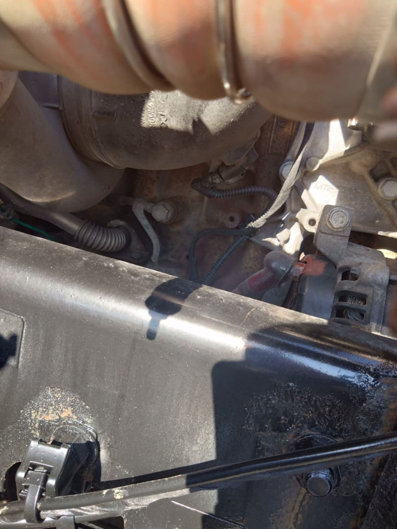 Engine bay view of a 2020 Freightliner Cascadia showing visible hoses, wiring, and components under the hood. Partial engine block and intake seen.