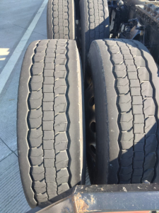 Trailer axles with twin tires showing tread pattern and surface wear in service condition.