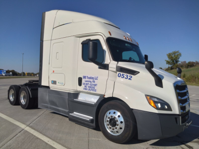 Truck cab side view showing Freightliner Cascadia sleeper with number 0532 on door, VIN plate area and wheel, highway parking lot.