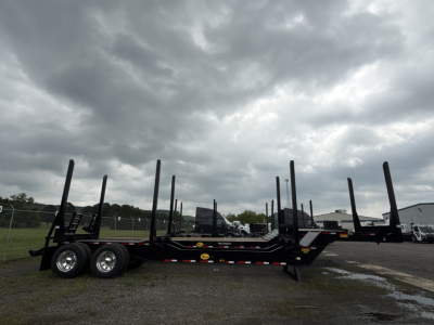Trailer chassis with multiple vertical posts for log loading, dual rear axles, black steel frame, overcast sky.