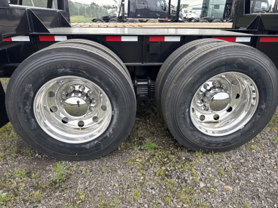 Twin rear axles with chrome wheels on a Viking log trailer showing dual tires and leaf spring suspension.